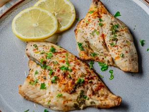 imagem de filetes de peixe com salsa picada e duas rodelas de limão